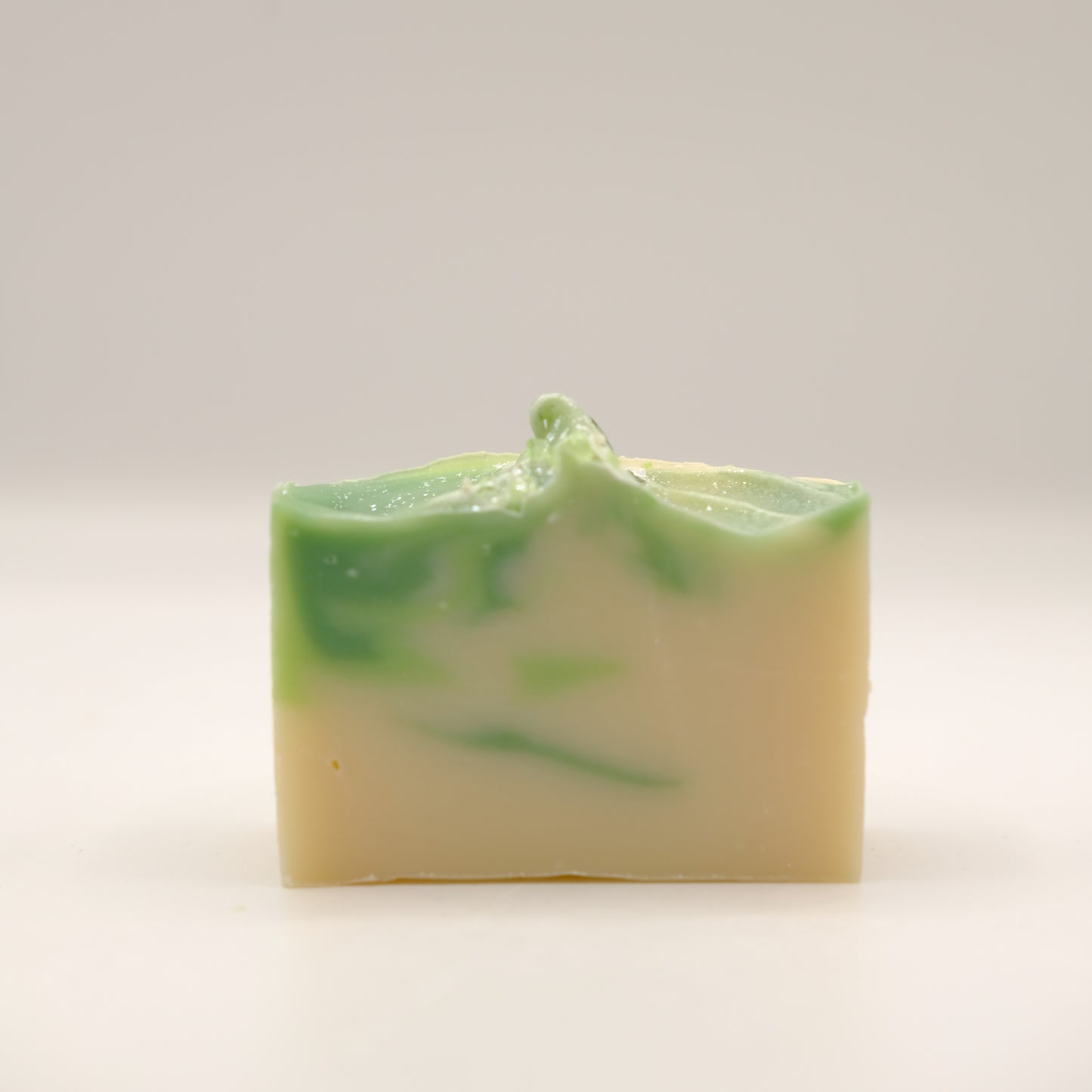 Green and white layered soap bar on a light gray background