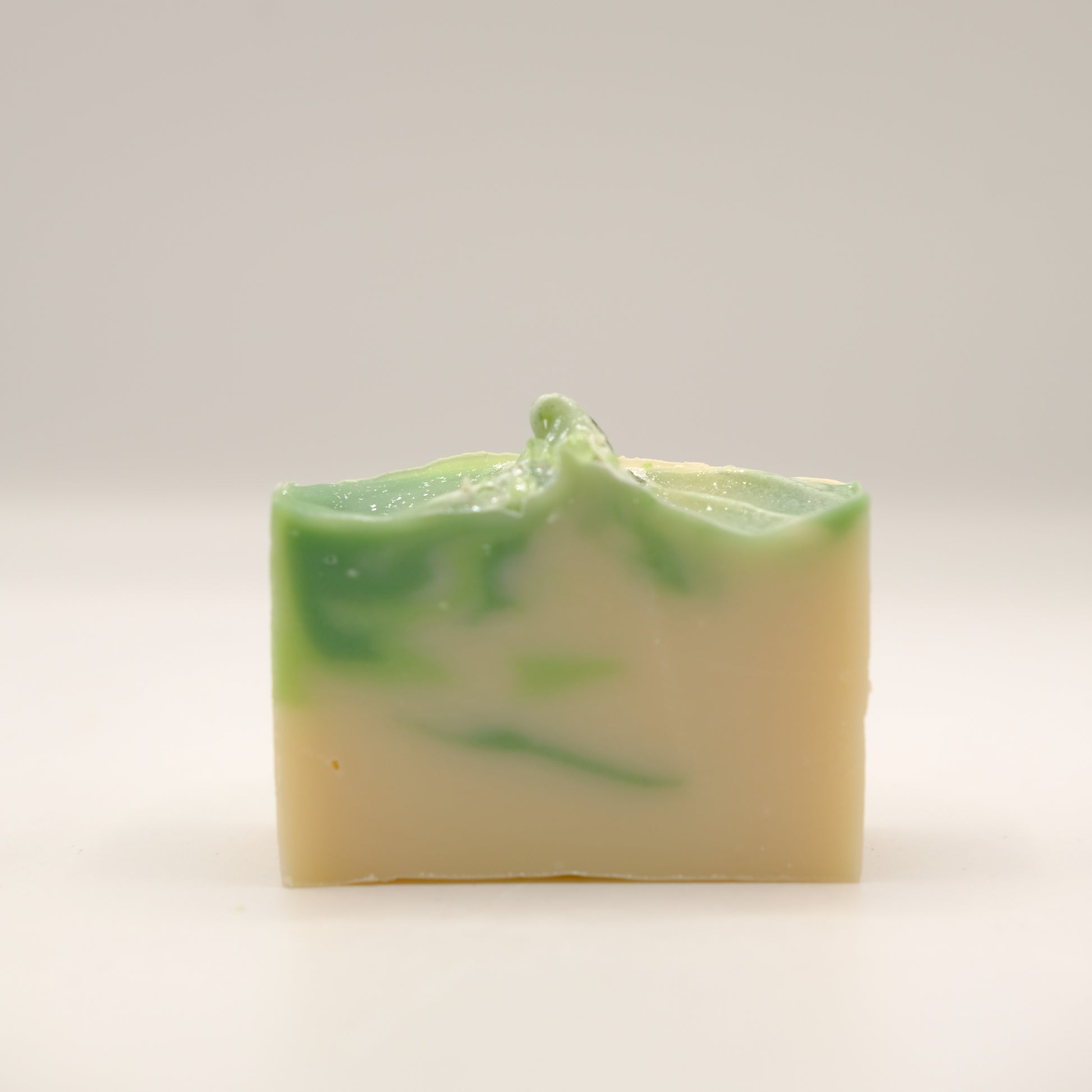 Green and white layered soap bar on a light gray background
