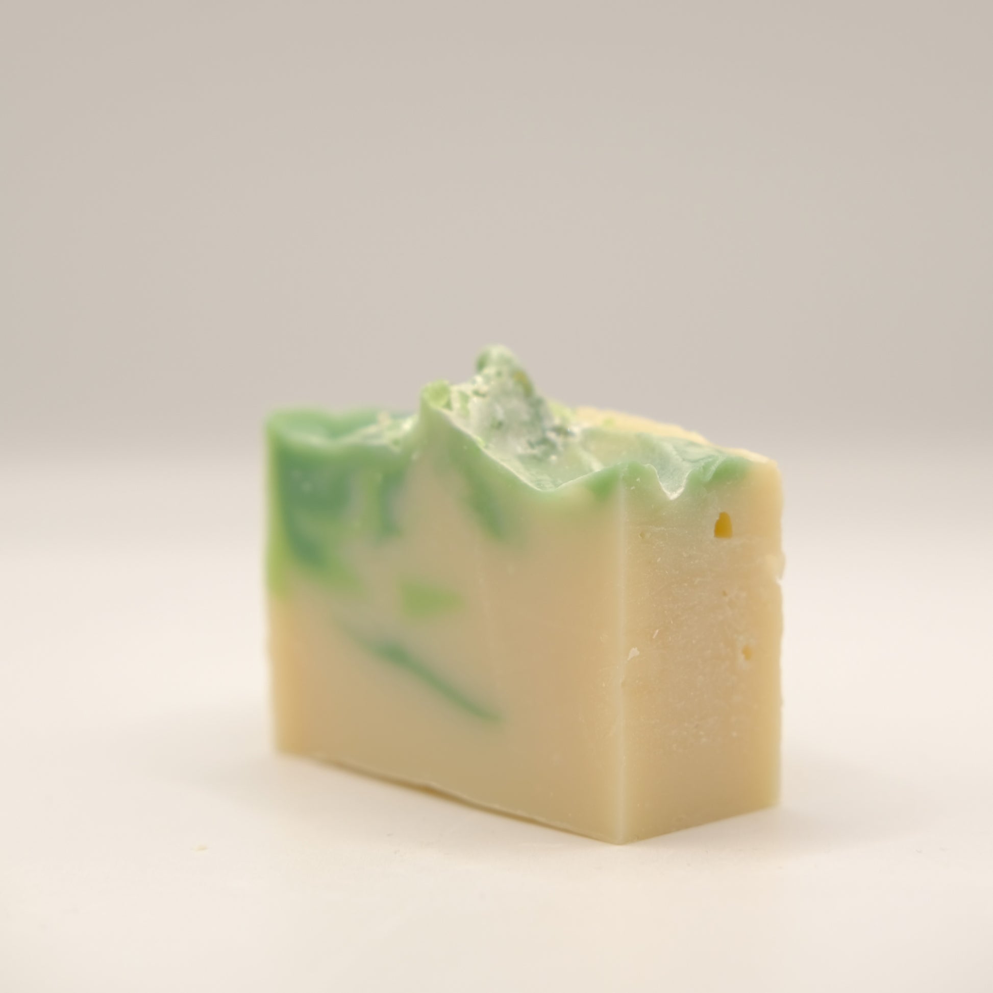 Bar of soap with green swirls on a light gray background