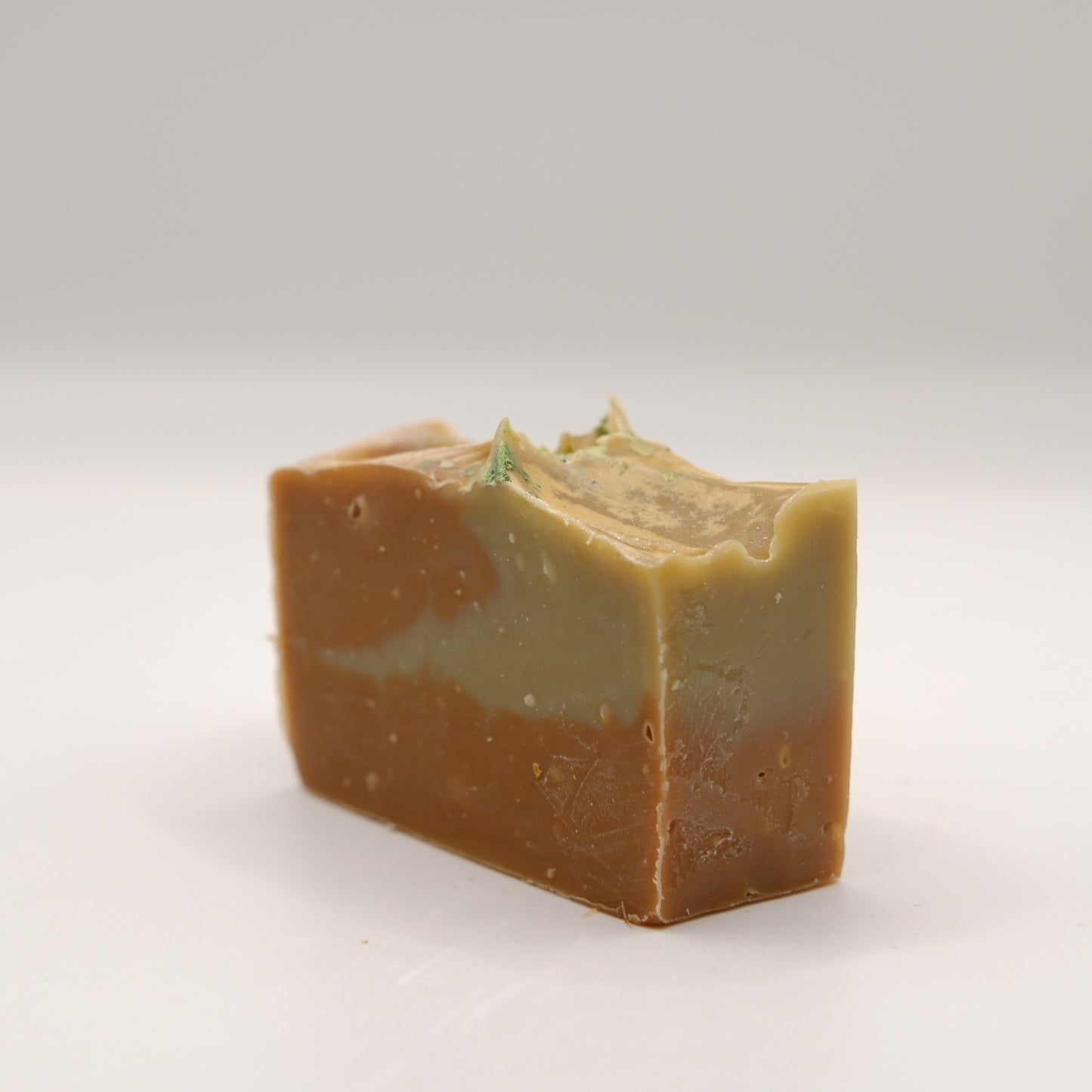 Block of brown and muddy green soap on a white background