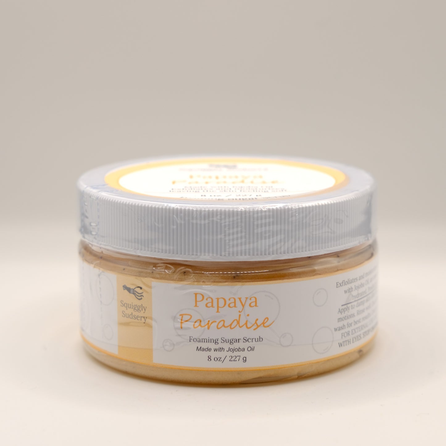 Jar of Papaya Paradise foaming sugar scrub on a beige background