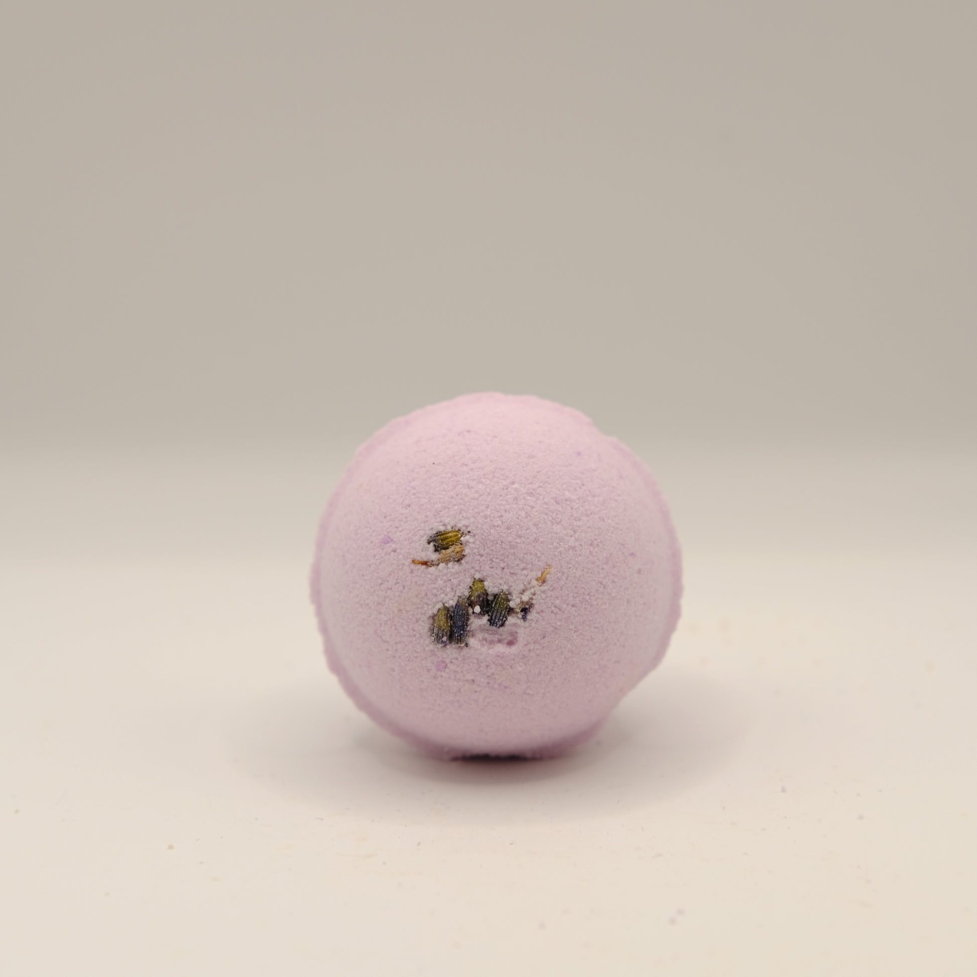 Purple bath bomb with decorative elements on a beige background