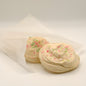 Two sugar cookies made out of soap with colorful sprinkles on a white surface