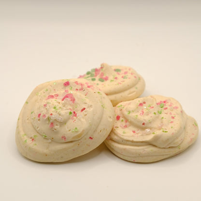 Three sugar cookies made out of soap with colorful sprinkles on a beige background