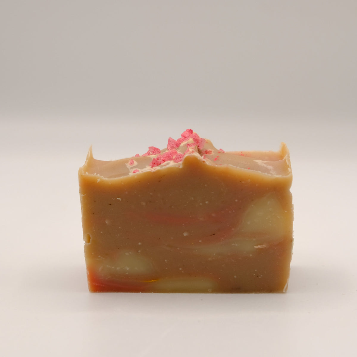 Bar of soap with pink specks on a white background