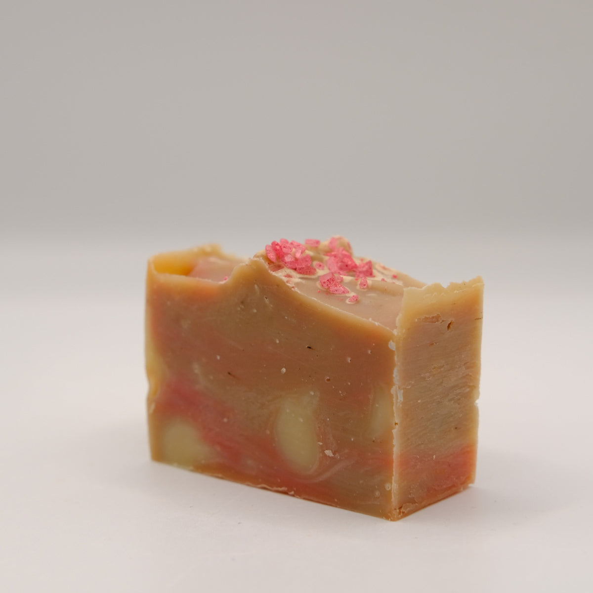Brown bar of soap with pink specks on a gray background