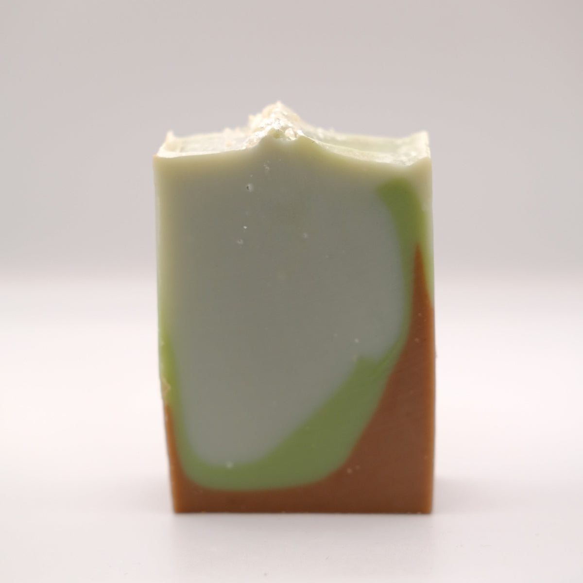 Bar of soap with green and brown gradient on a white background