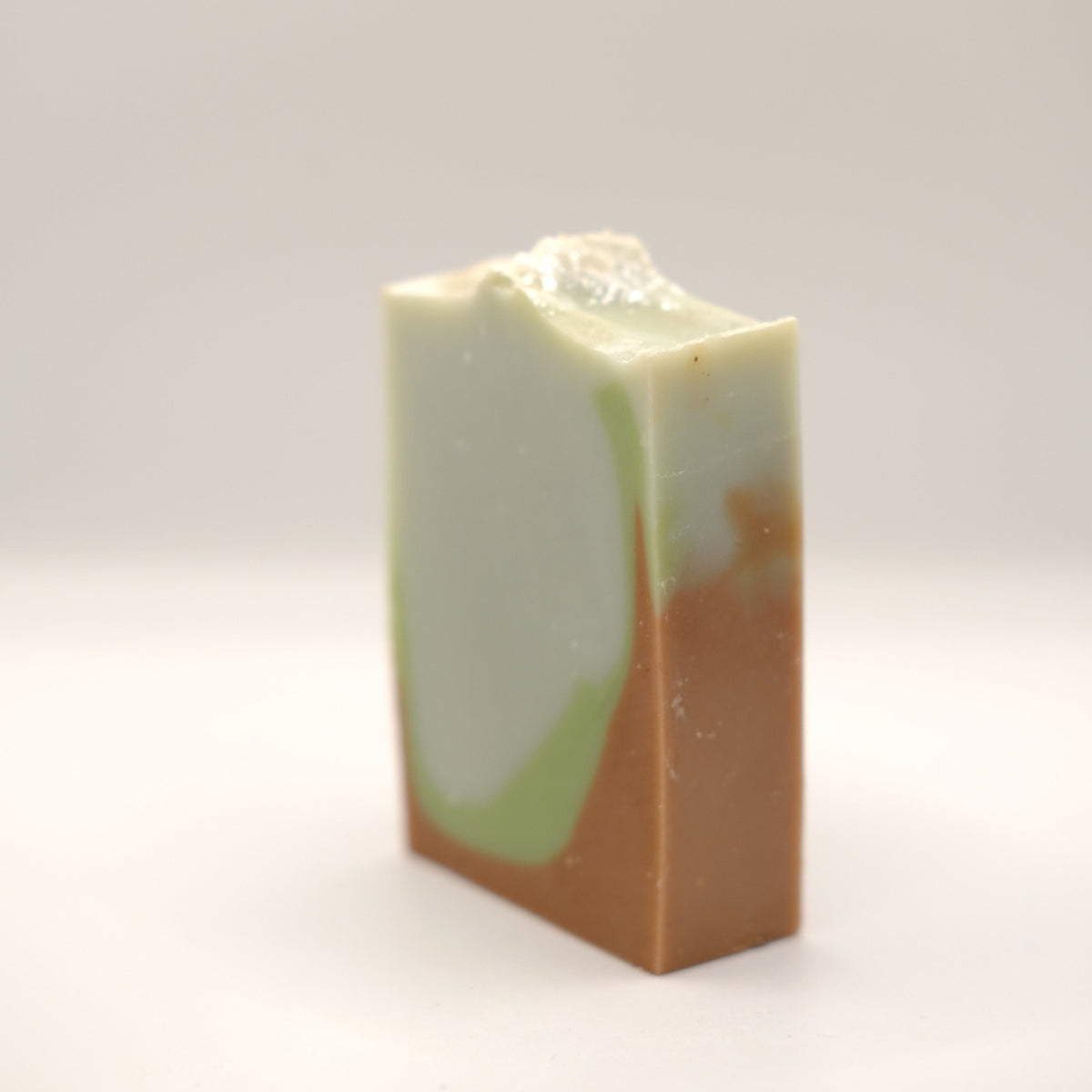 Rectangular bar of soap with a gradient from green to brown on a white background