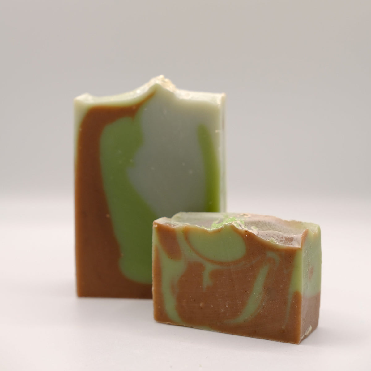Two swirled soap bars, one larger and one smaller, on a light gray background.