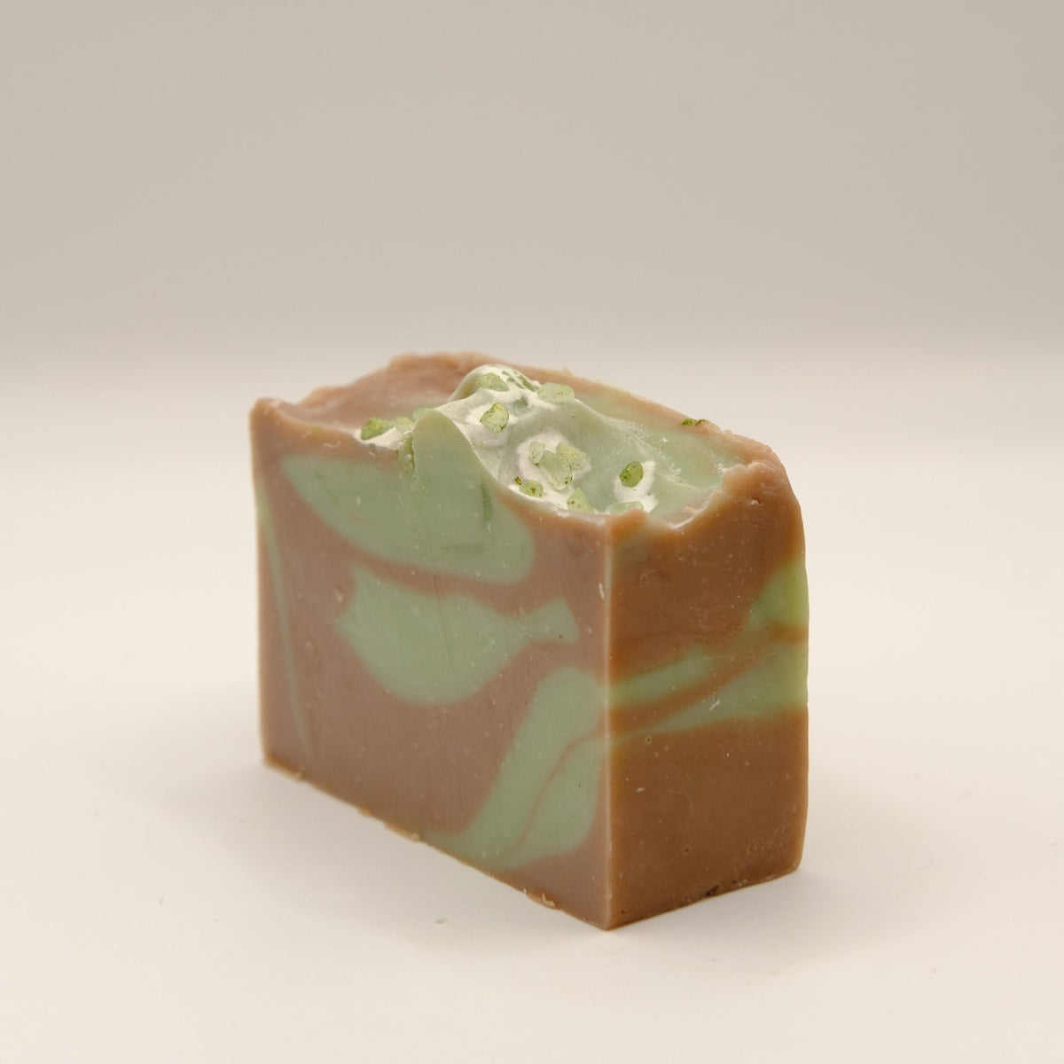 Bar of soap with green and brown swirl on a light background
