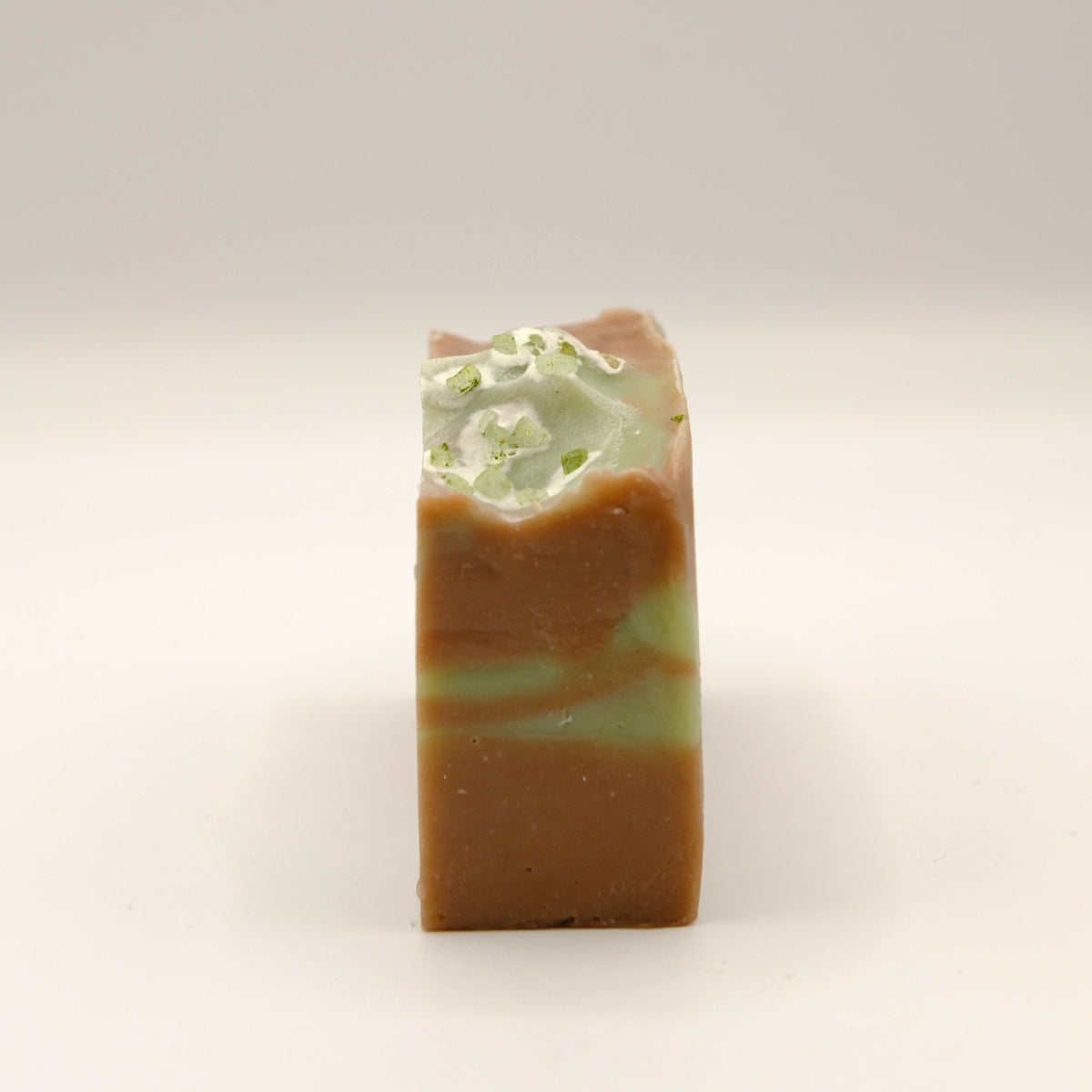 Bar of soap with green and brown swirled pattern on a light background