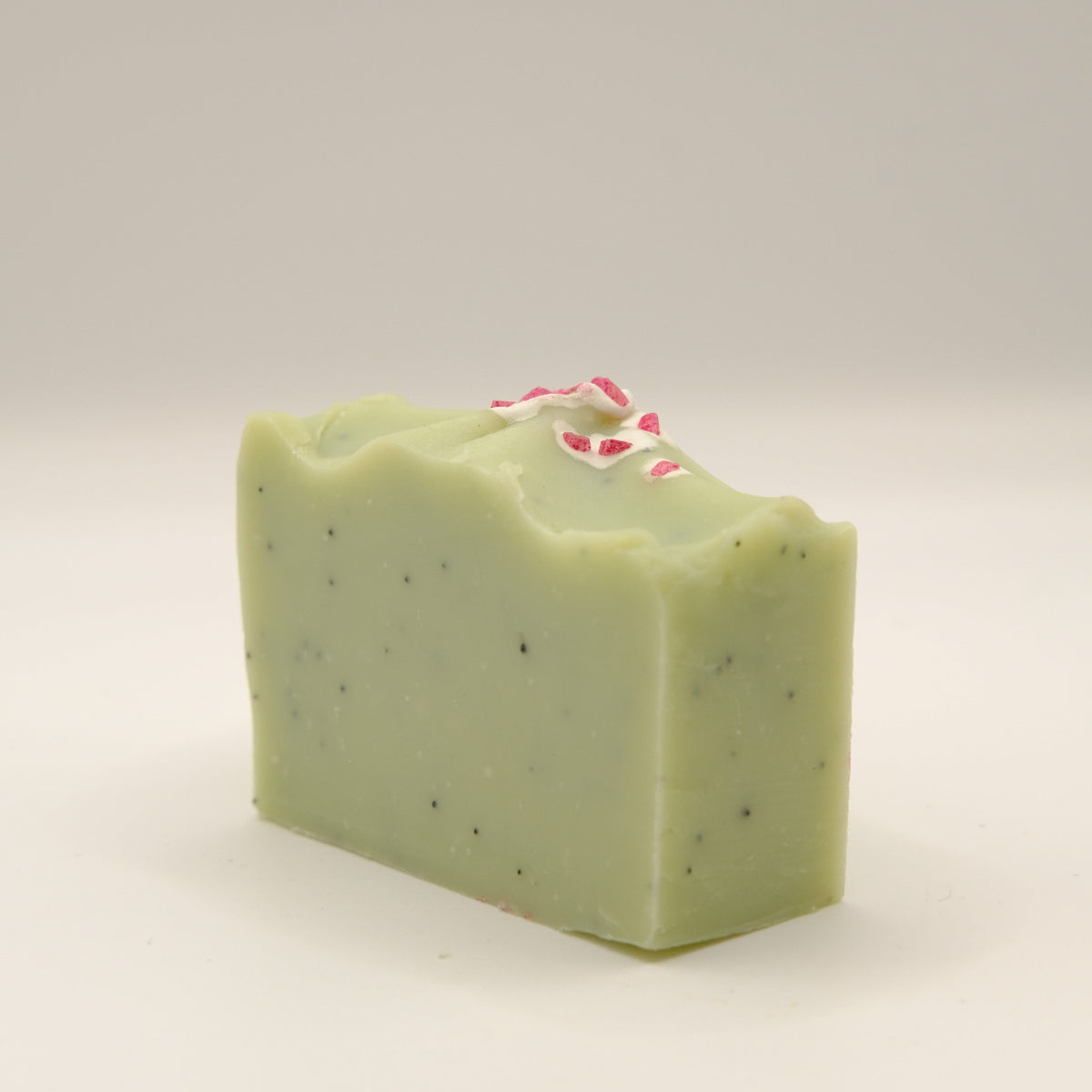 Green soap bar with specks on a light gray background