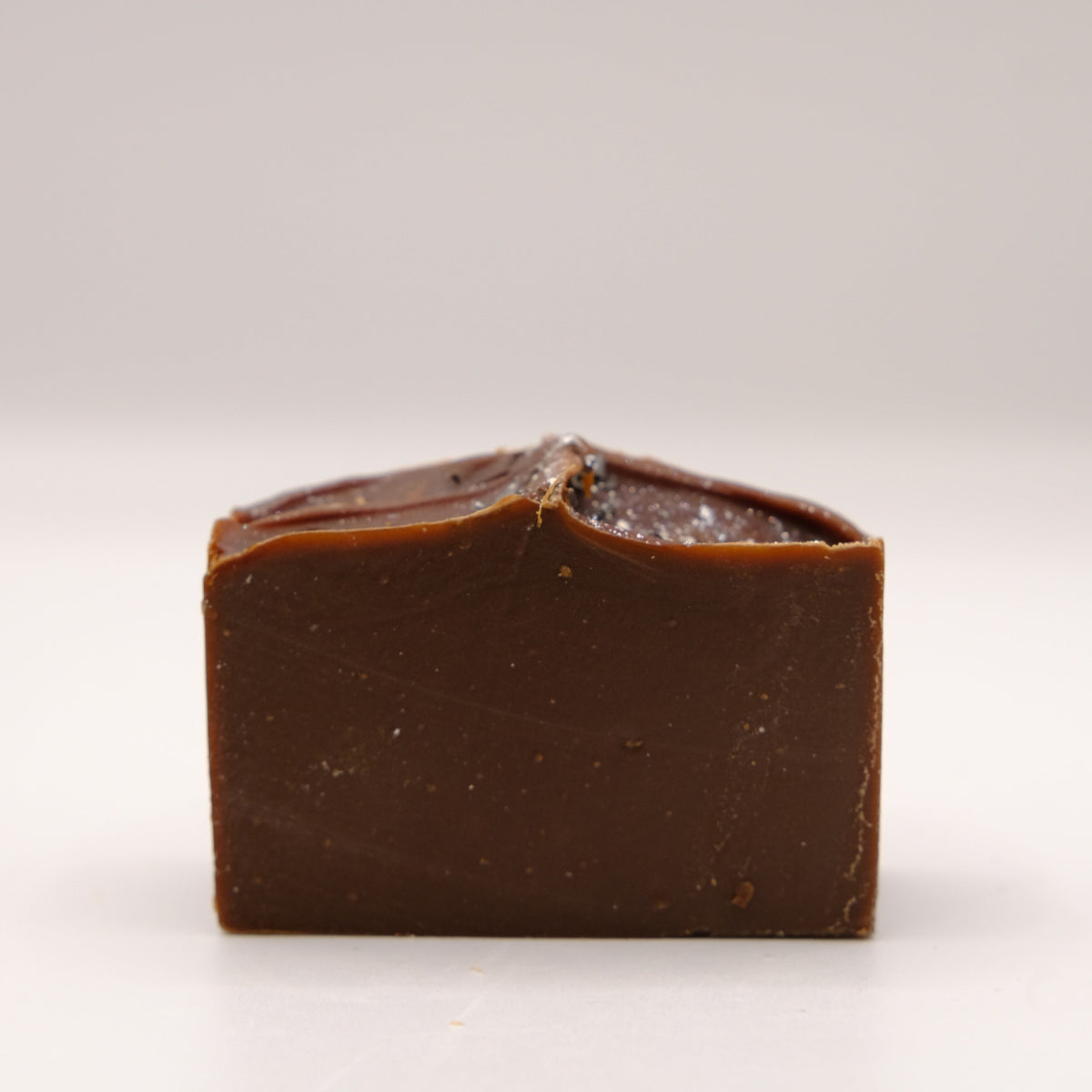 Dark brown bar of soap on a white background
