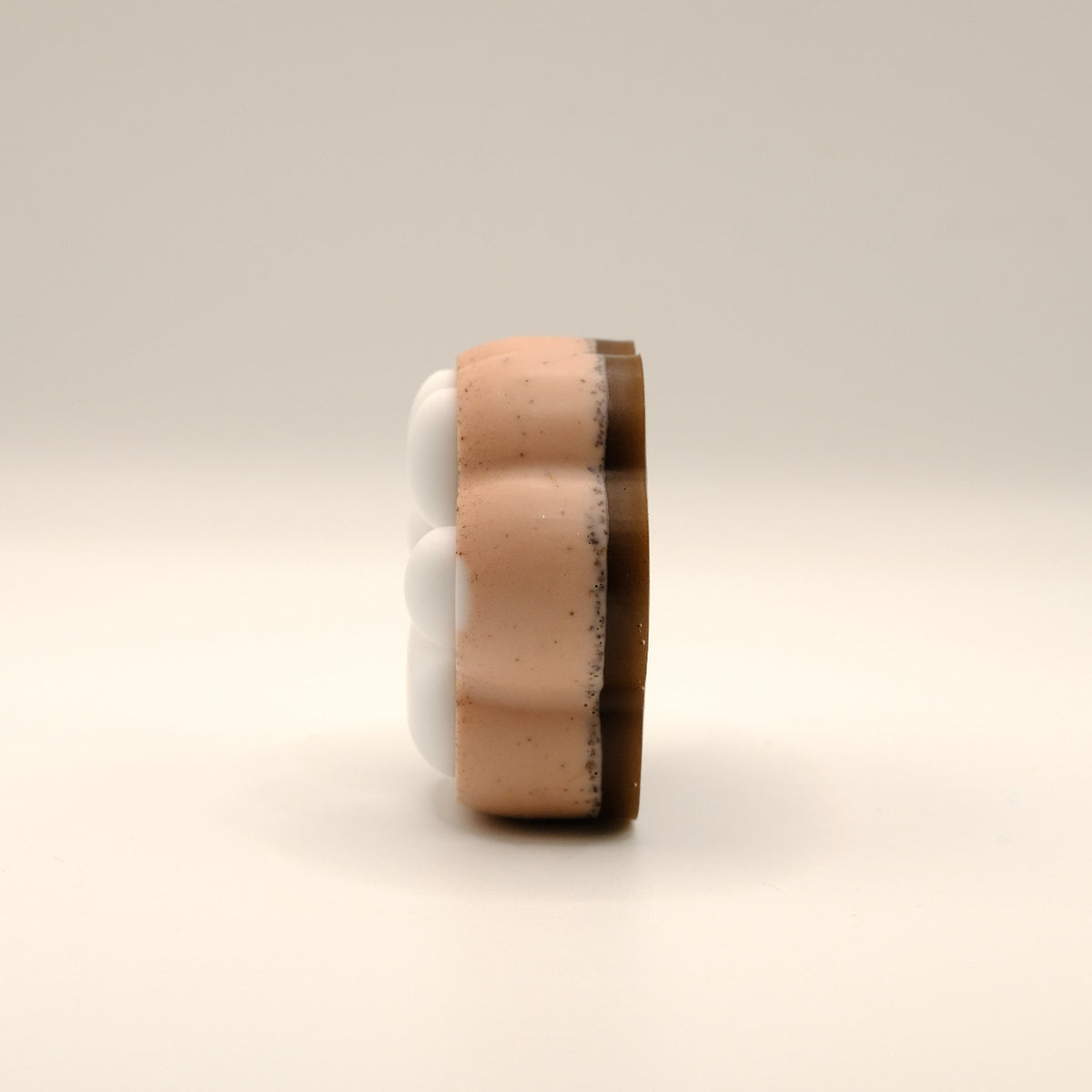 Brown and white soap bar shaped like a paw print on a beige background