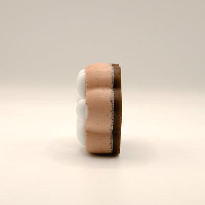Brown and white soap bar shaped like a paw print on a beige background