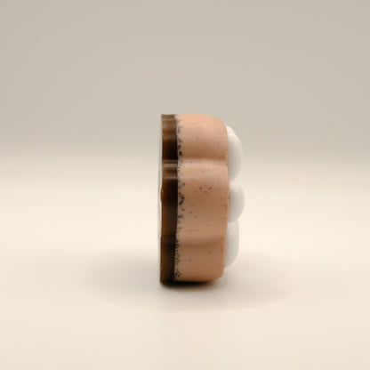 Brown and white soap bar shaped like a paw print on a beige background