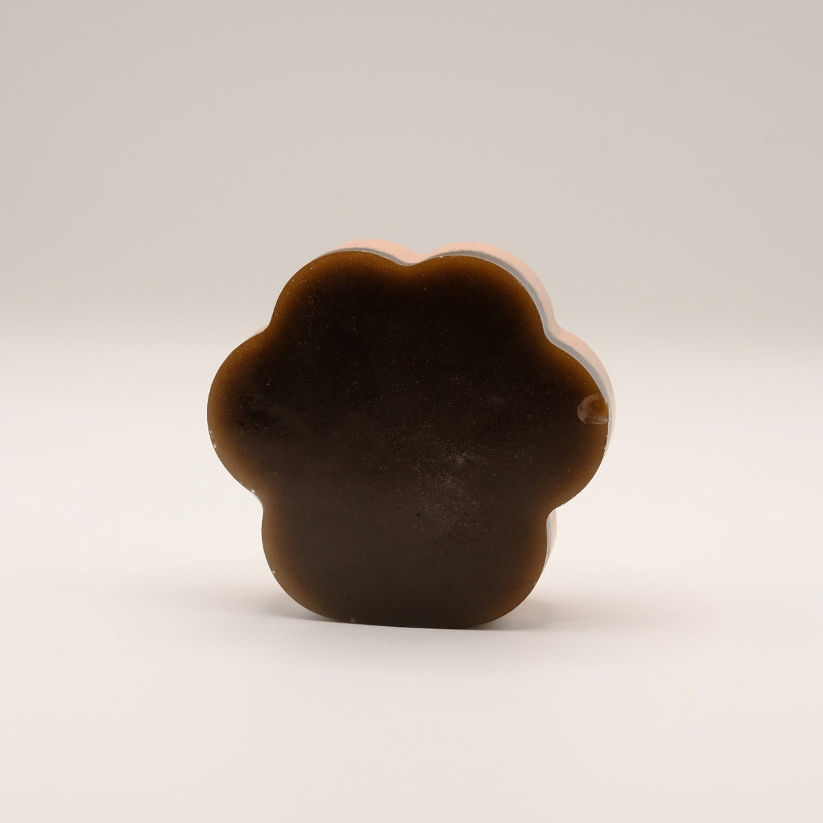 Brown soap bar shaped like a paw print on a beige background