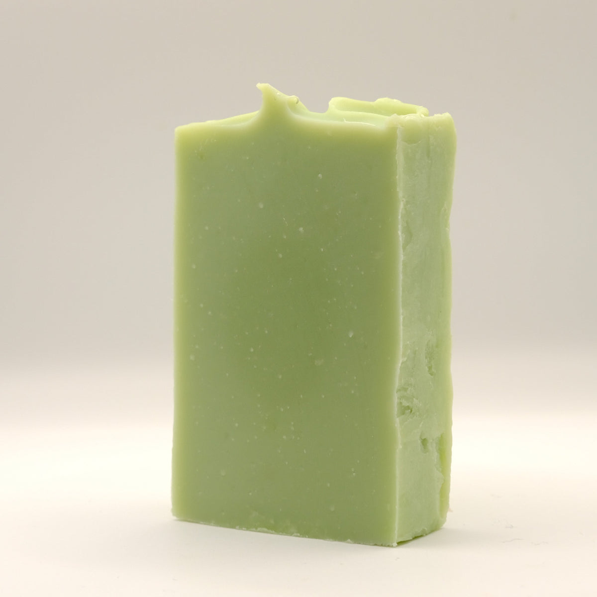 Green bar of soap with a textured top on a light gray background