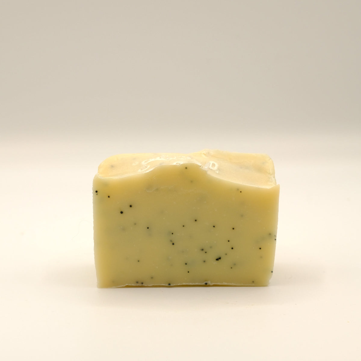 Yellow bar of soap with specks on a light background