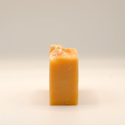 Side view of orange bar of soap with a white background