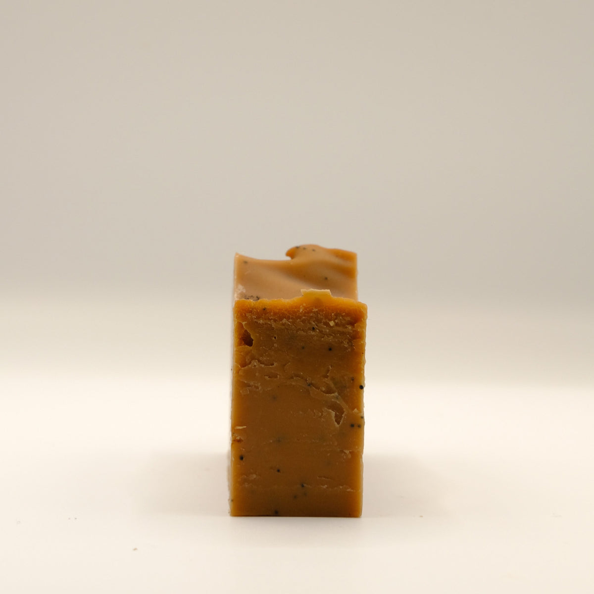 Bar of brown soap on a light beige background