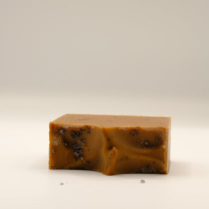 Bar of brown soap with specks on a beige background