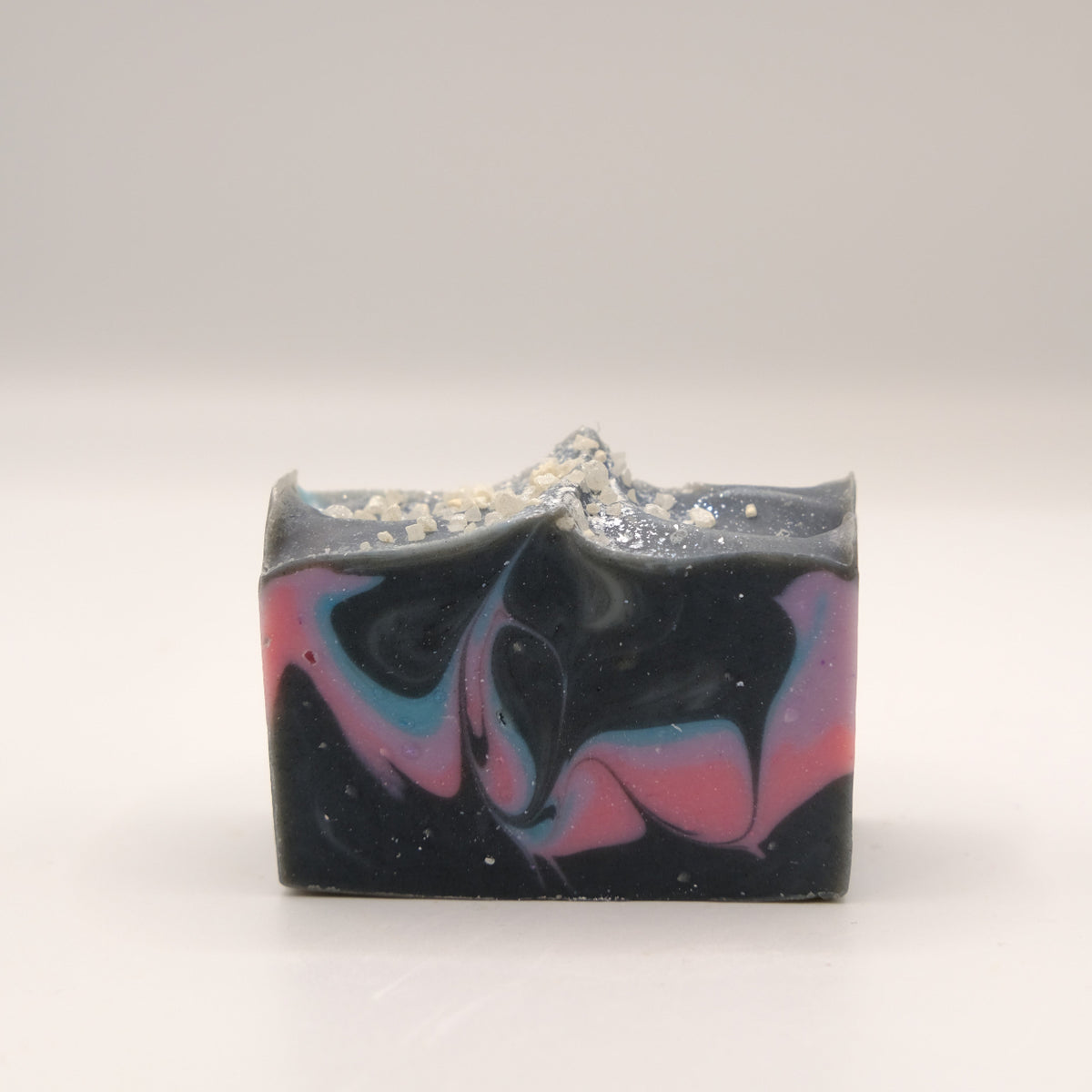 Bar of soap with black, pink, purple, and blue swirls on a white background