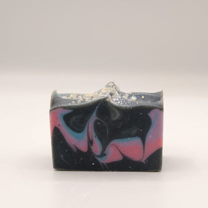 Bar of soap with black, pink, purple, and blue swirls on a white background
