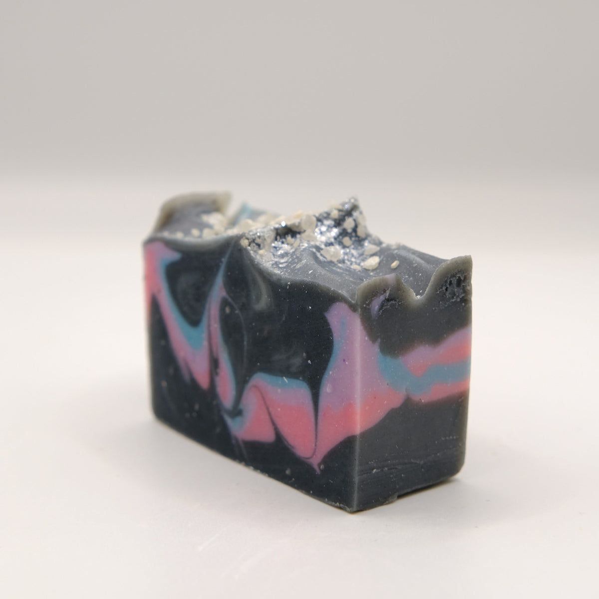 Bar of soap with black, pink, purple, and blue swirls on a white background