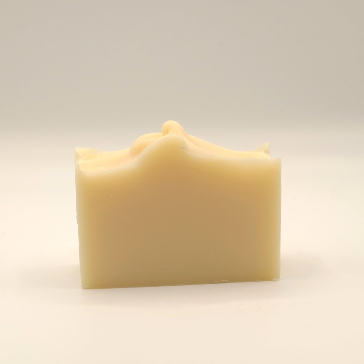 Beige soap bar with a textured top on a light beige background