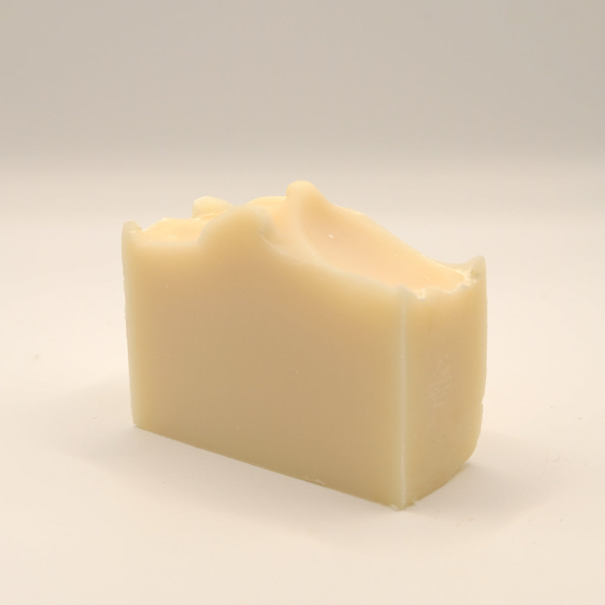Beige soap bar with a textured top on a light surface.