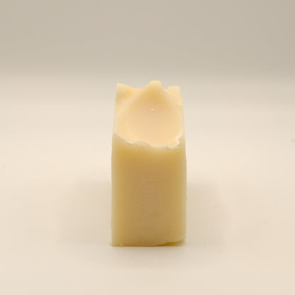 Beige bar of soap with a texture top on a light surface