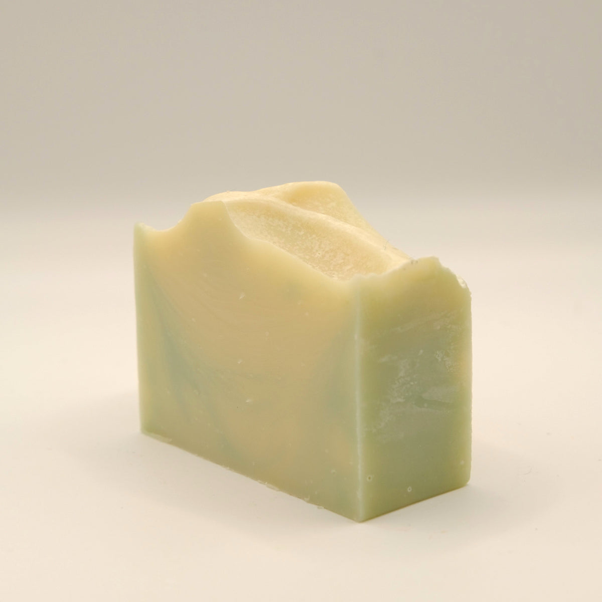 Bar of soap with a yellow and green swirl on a light gray background