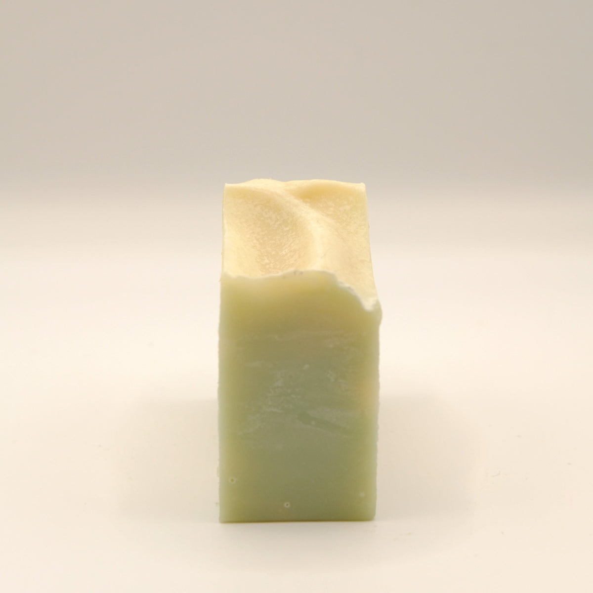 Rectangular bar of soap with a gradient from light to dark green on a beige background