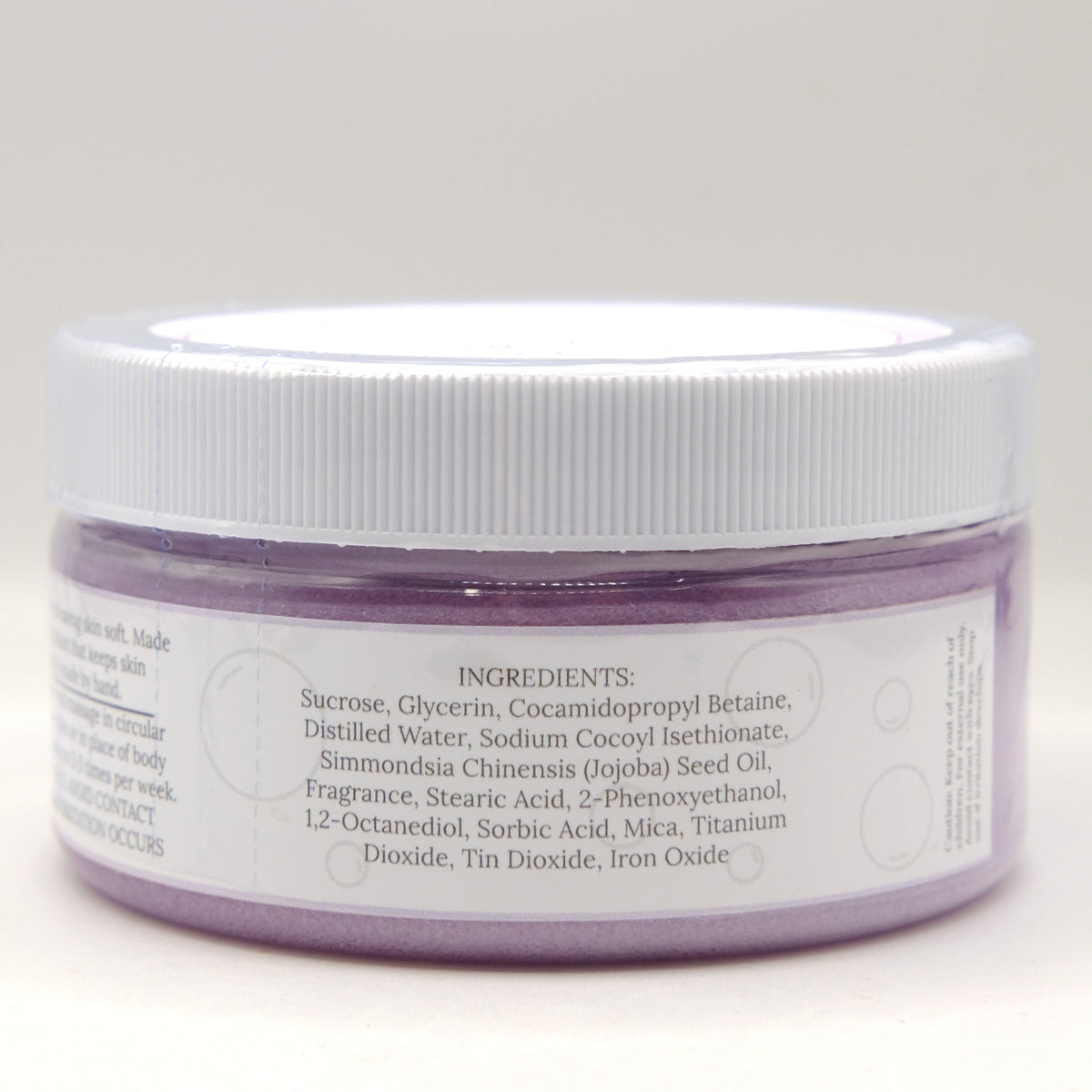 Jar with a white lid and purple sugar scrub on a light gray background
