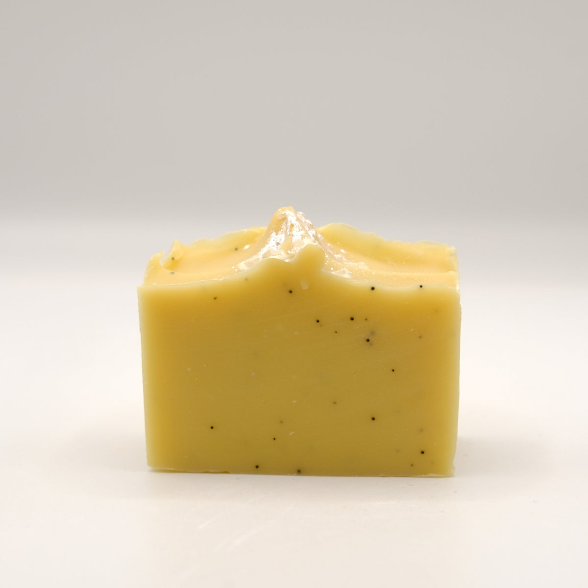 Yellow soap bar with specks on a white background