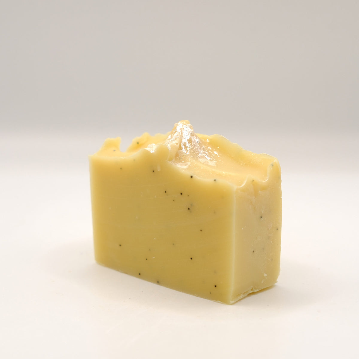 Yellow soap bar with specks on a white background