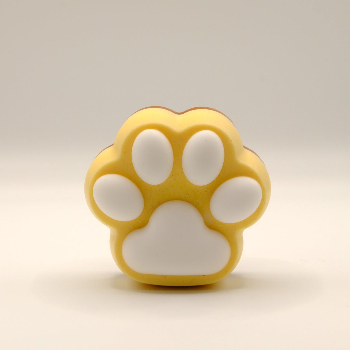 Brown, yellow and white soap bar with a paw print design on a light gray background