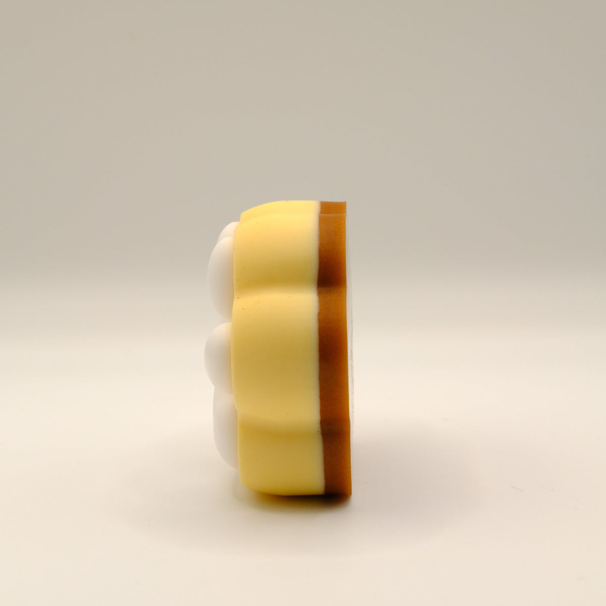 Brown, yellow and white soap bar with a paw print design on a light gray background