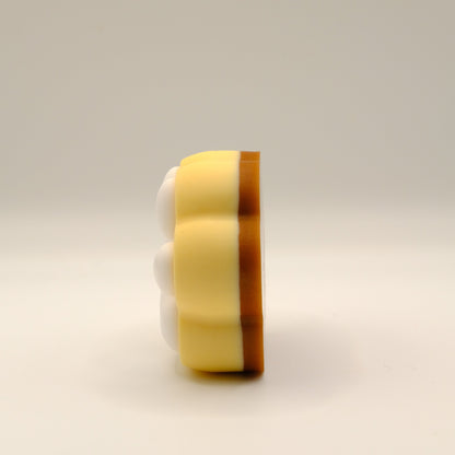 Brown, yellow and white soap bar with a paw print design on a light gray background