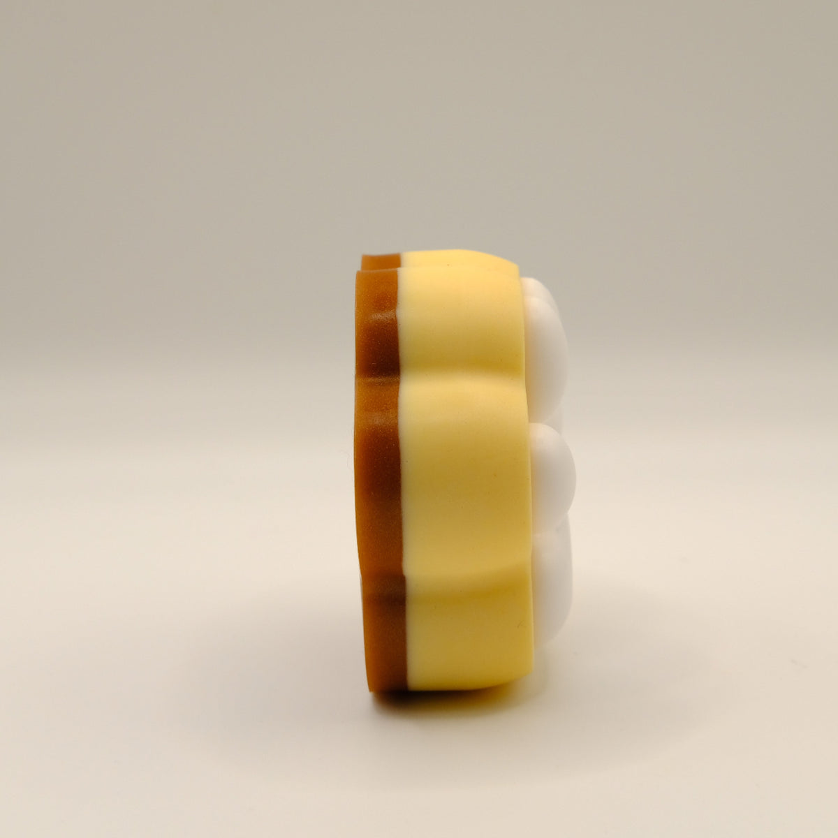 Brown, yellow and white soap bar with a paw print design on a light gray background