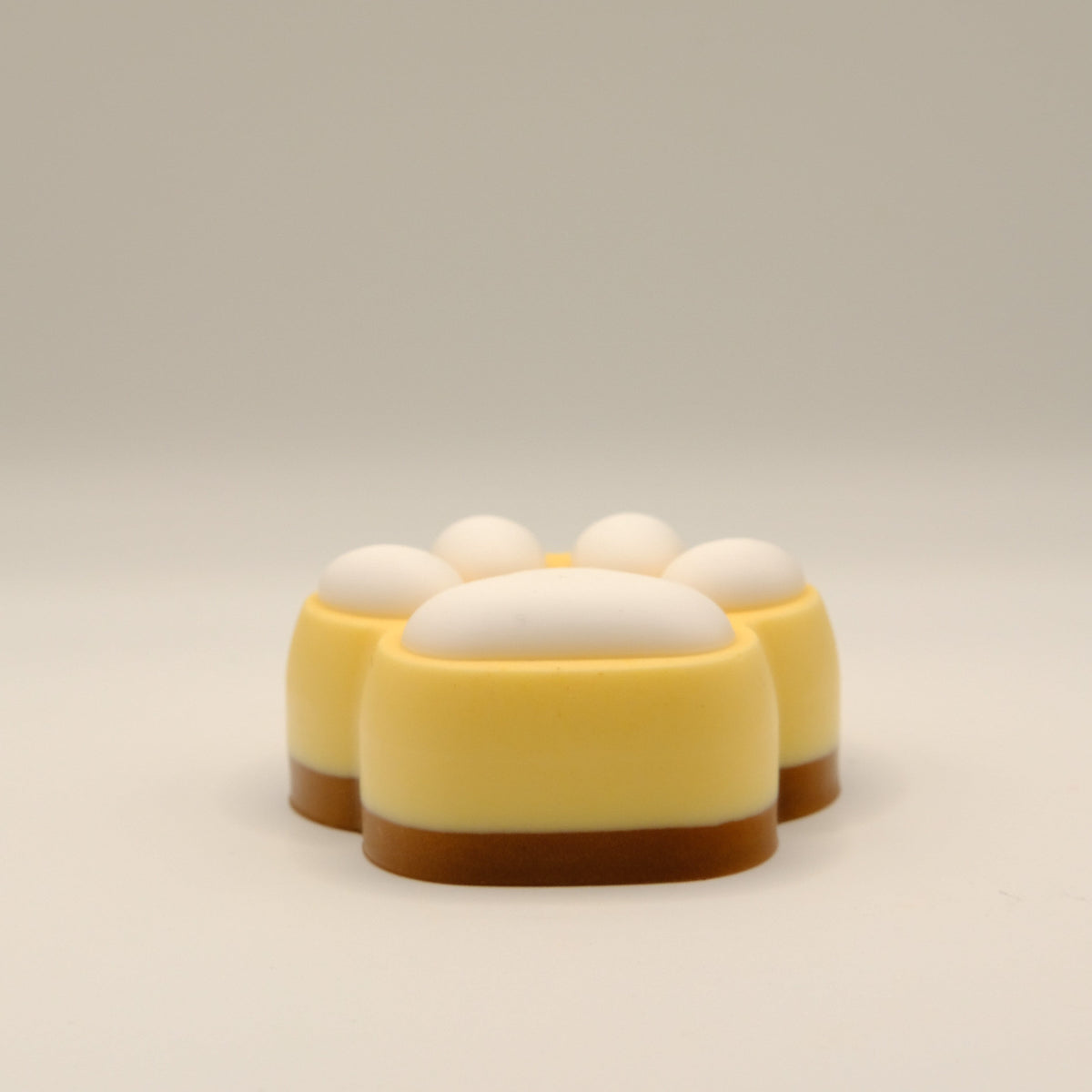 Brown, yellow and white soap bar with a paw print design on a light gray background