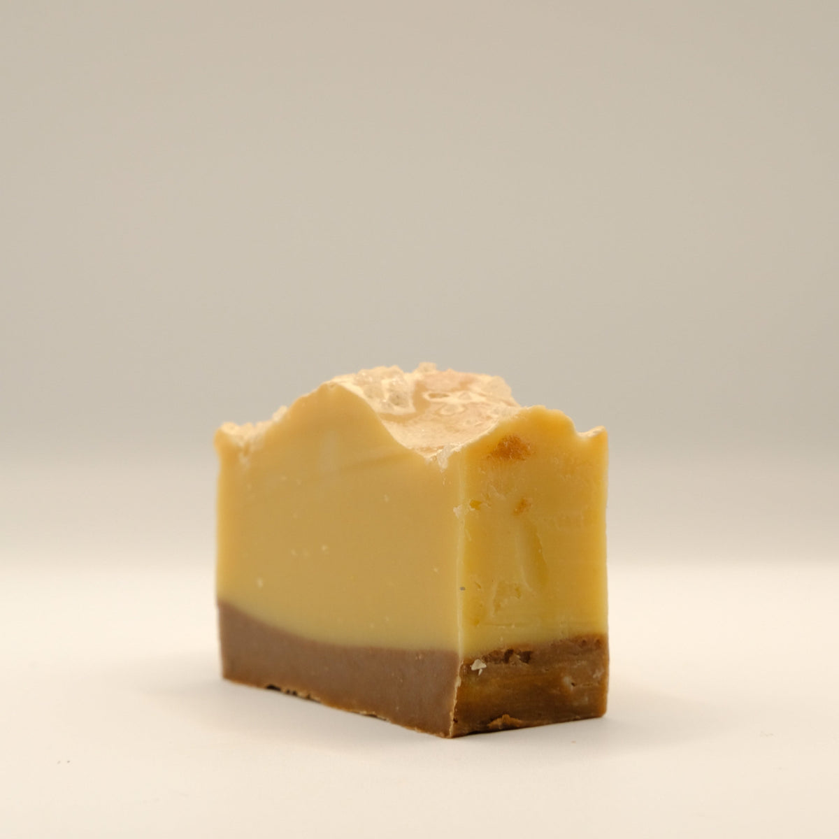 Bar of soap with a yellow and brown two-tone color on a light gray background