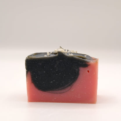 Bar of soap with black and pink layers on a white background