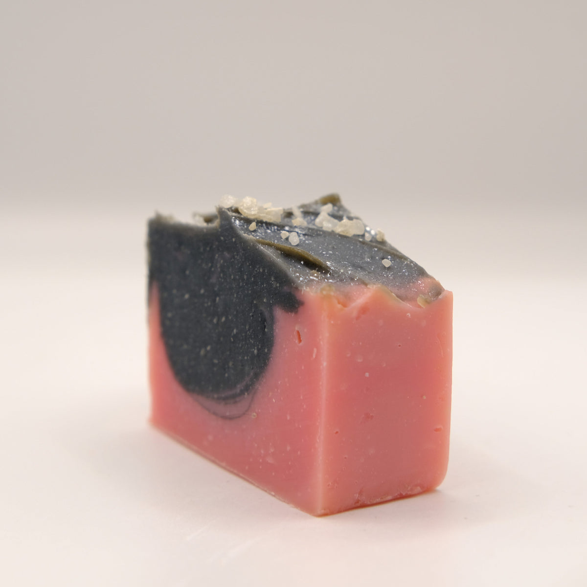Bar of soap with a black and pink coloration on a light gray background