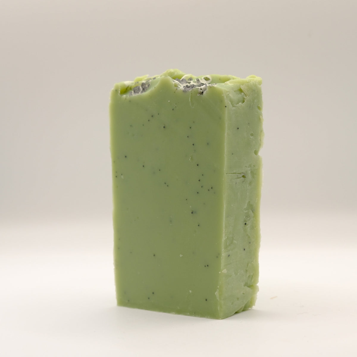Green soap bar with specks on a light gray background
