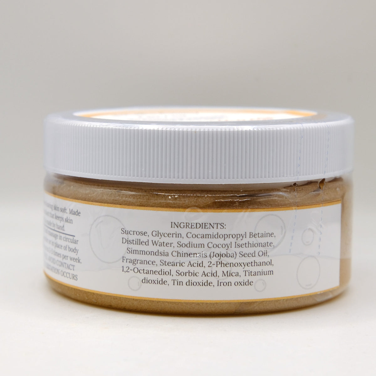 Jar of brown sugar scrub with a white label on a light gray background