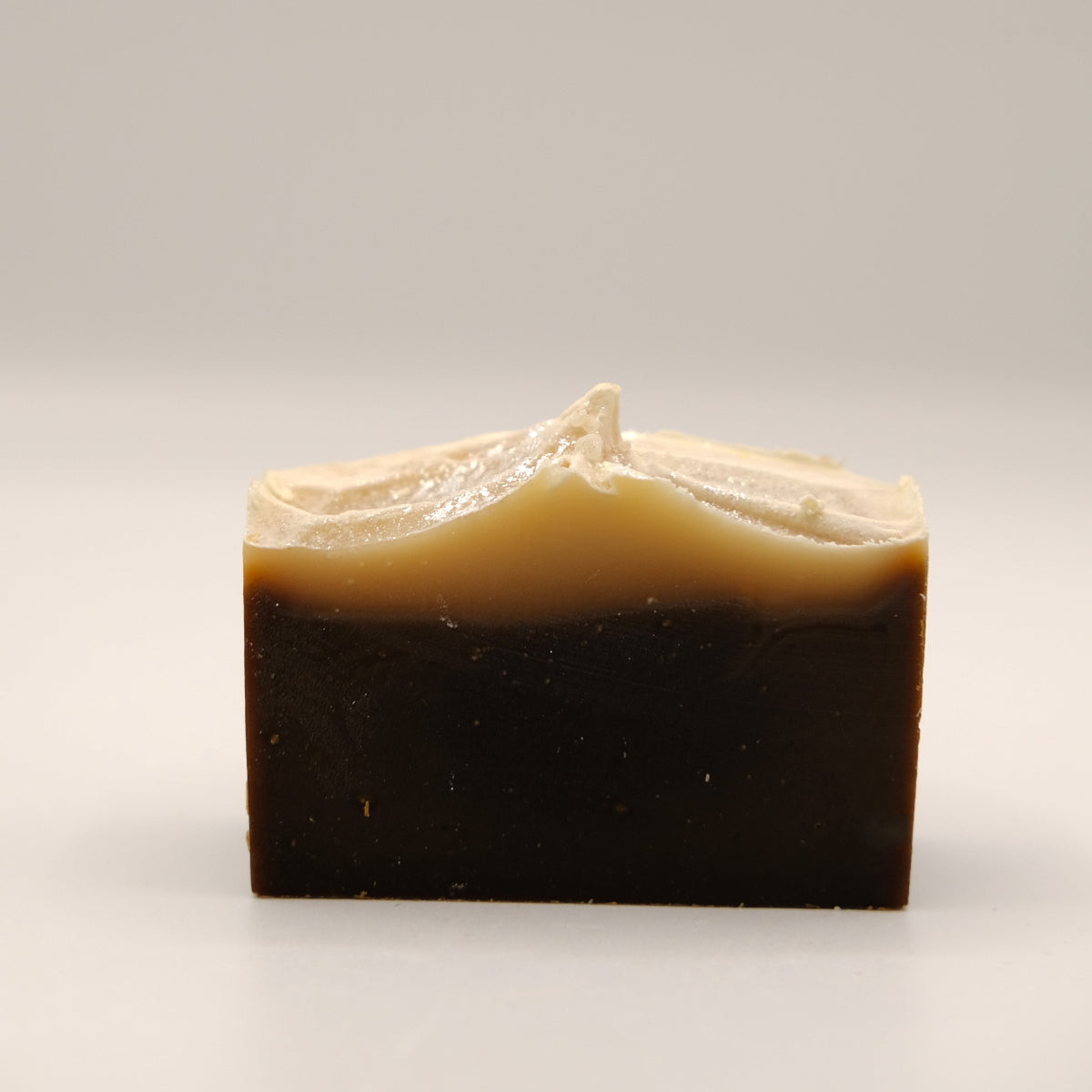Bar of soap with a two-tone brown and beige color on a light gray background