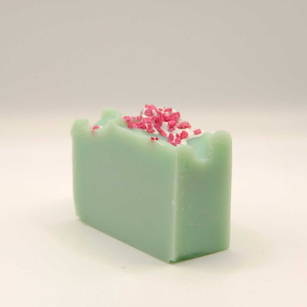 Green soap bar with pink specks on a light gray background