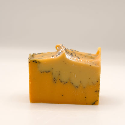 Bar of yellow and orange soap with specks on a white background